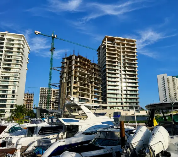 boats docked in harbor with apartment contruction in background